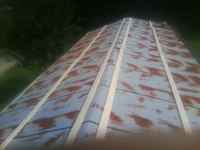 Rusted metal roof panels with new wood purlins before replacement — Storm Damage Roof Repair in Oswego by Roofing Brothers