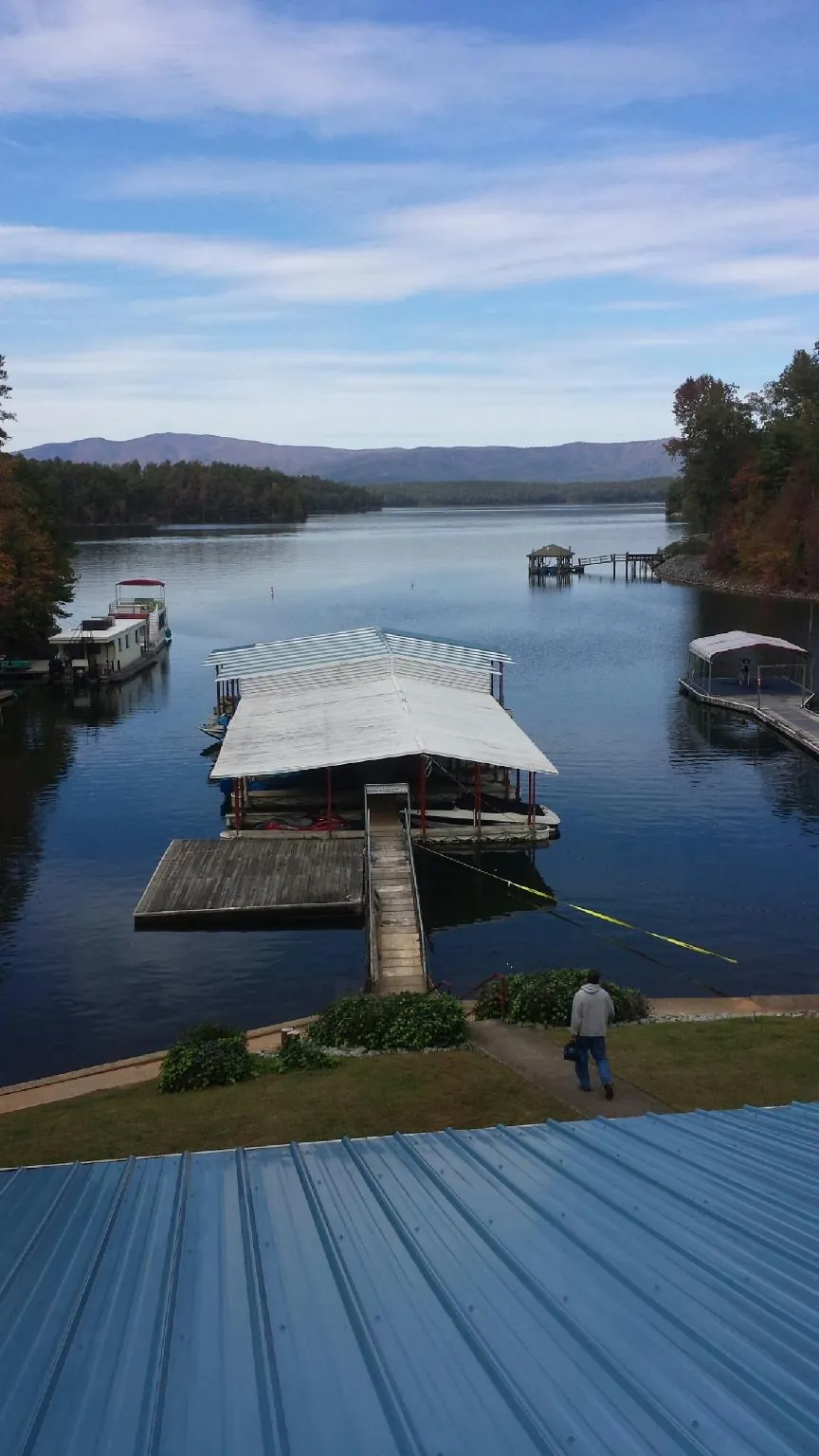 View across a lake from a newly installed blue metal roof in Oswego